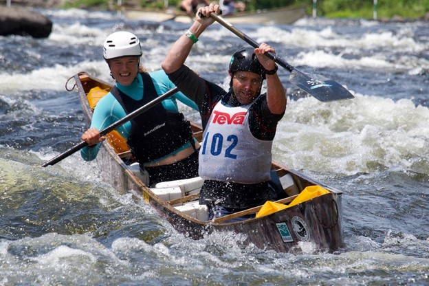 Two people piloting a canoe down a flowing river.