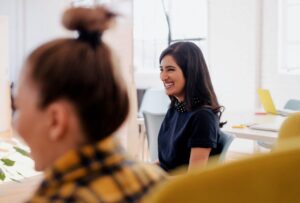 Two women sitting in an office smiling.