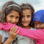 A photo of three young female newcomers hugging.