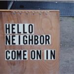 A business street sign that reads, “Hello Neighbor - Come On In.